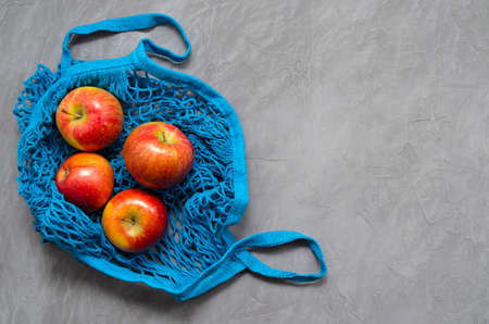 blue mesh eco zero waste shopping bag with fruit red apples, top view on ultimate gray background, close up with space for textの写真素材