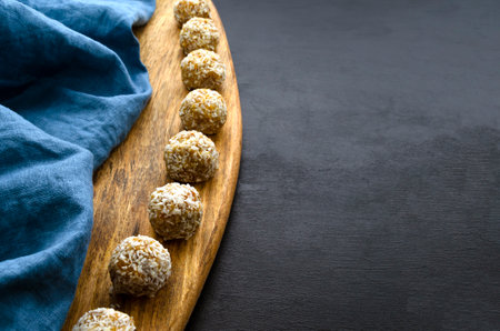 nutritious energy balls consisting of nuts, oatmeal, honey, dried fruits on a wooden board on a black slate background with a blue towelの写真素材