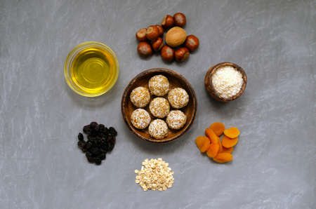 energy vegetarian balls and ingredients for their preparation on a grey slate background. nuts raisins coconut honey and dried apricots. recipe for a nutritious breakfast or snack.の写真素材