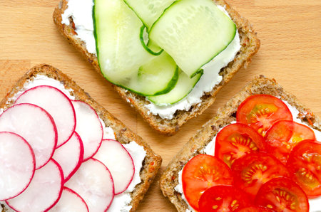 Vegetarian sandwiches with cream cheese, fresh cucumber, radish, tomatoes on a cutting wooden board on a concrete background. Flat lay. healthy food diet slimming fitness. close-up.の写真素材