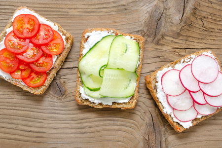 appetizing delicious vegetarian sandwiches with cream cheese, fresh cucumber, radish, tomatoes on a wooden background. Flat lay. healthy food diet slimming fitness. with place for text. close-upの写真素材