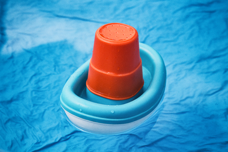 children's toy boat of blue color swims in the poolの写真素材