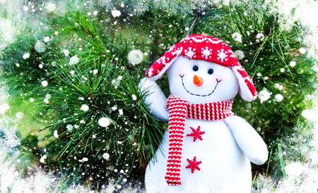 snowman in a red hat and scarf on a Christmas tree backgroundの写真素材
