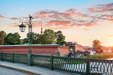 Lantern with an arrow on the Ioannovsky Bridge and the Peter and Paul Fortress in the rays of the sunsetのeditorial素材