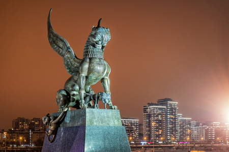 Sculpture of a winged leopard female with cubs against the background of an orange night sky near the center of the family in the city of Kazanの写真素材