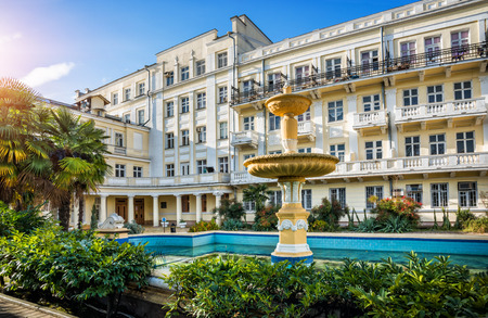 Yellow Primorskaya hotel in sunny Sochi and a swimming pool with a fountain in front of the buildingのeditorial素材