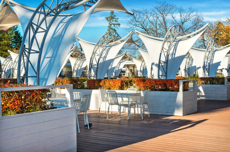Empty street cafe at VDNH in Moscow with white chairs and tables on a sunny autumn day