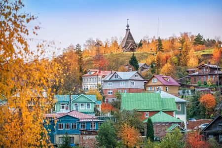 View of Levitan Mountain with a church and houses among red autumn trees on a cloudy afternoonの写真素材