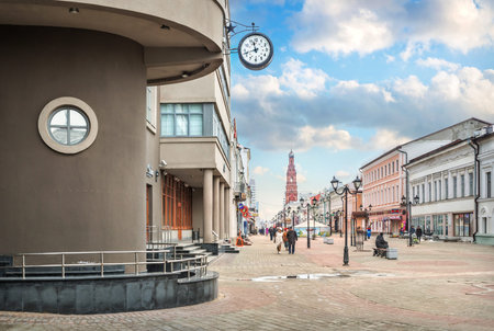 Clock on a building on Bauman Street in Kazan and a view of the high bell tower on a sunny spring...