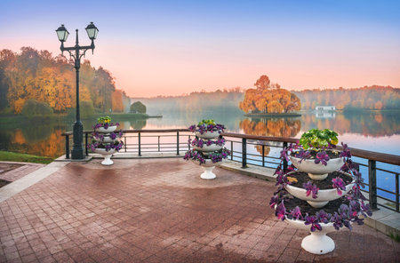 An island in Tsaritsyno Pond in Moscow among the morning haze and golden autumn trees and flower beds on the shoreの写真素材