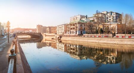Residential elite complex on Ozerkovskaya Embankment of the Vodootvodny Canal in Moscow with reflection in the water on an early sunny morning and the Small Krasnokholmsky Bridgeの写真素材