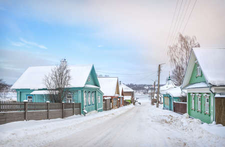 Wooden houses on Nikolskaya Street and a view of the frozen Volga in Plyos in the light of a winter day under a blue skyの写真素材