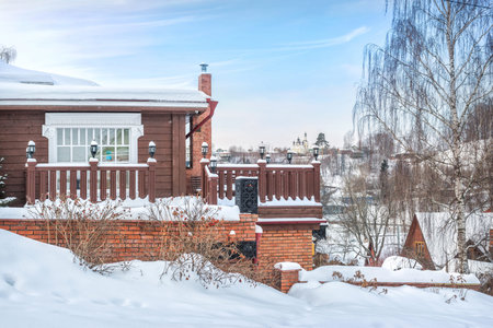 Wooden veranda of the museum in the snow and a view of the temple in the distance in Plyos in the light of a winter day under a blue skyのeditorial素材