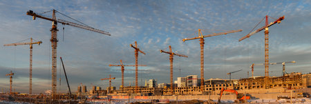 Panoramic view of a large construction site with many tower cranes. New residential area of a big...