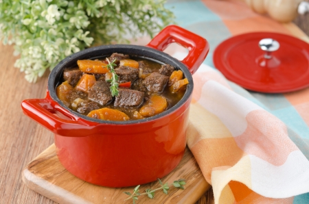 stew of beef with vegetables and prunes in a red cast iron pan の写真素材