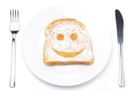 Toast with a smile of powdered sugar on a plate, fork and knife isolated on a white backgroundの写真素材