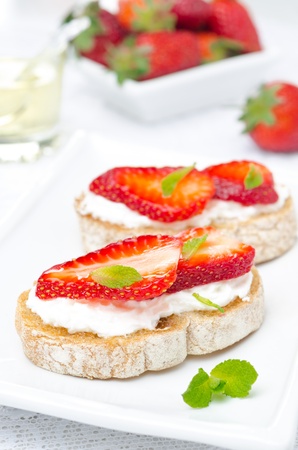 bruschetta with goat cheese, fresh strawberries and mint on the plate, verticalの写真素材