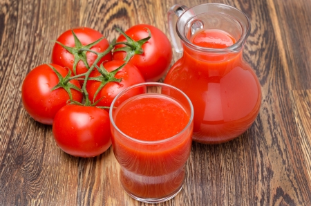 glass and jug of tomato juice, fresh tomatoes on wooden background horizontalの写真素材