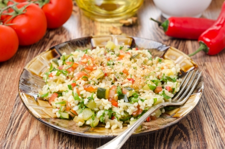 salad with bulgur, zucchini, tomatoes and parsley on a wooden tableの写真素材