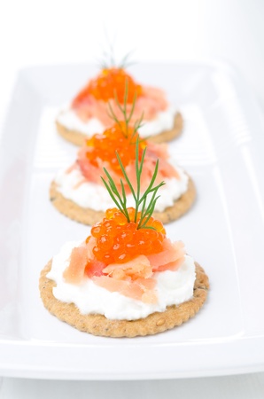 crackers with cream cheese, salted salmon and red caviar on the white plateの写真素材