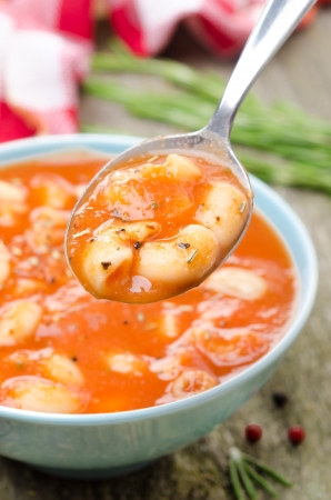 tomato soup with pasta, white beans and rosemary in a spoon, verticalの写真素材