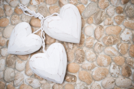 three white wooden heart on the background of stones, close-upの写真素材