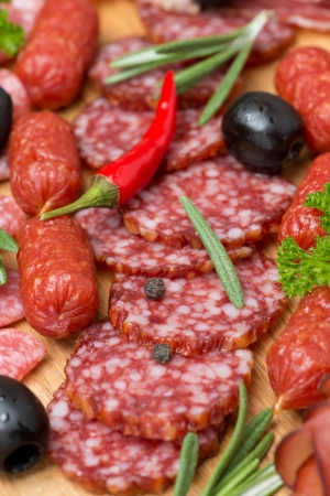 Assorted meats and sausages on a wooden board, close-up, verticalの写真素材