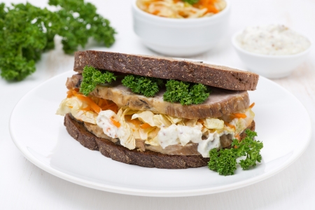 sandwich of rye bread with coleslaw and baked meat on the plateの写真素材