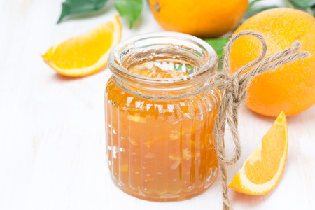 orange jam in a glass jar and oranges on the table の写真素材