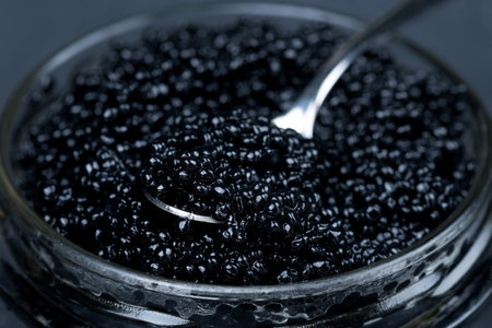 spoon of black caviar in a glass jar, selective focus, close-up