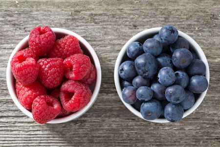 raspberries and blueberries in bowls, top view, horizontalの写真素材
