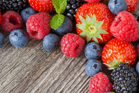 wooden background with fresh berries and mint, horizontal, top viewの写真素材