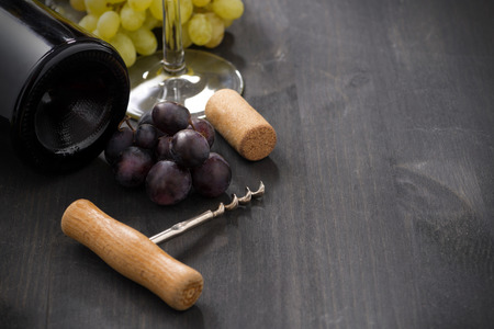bottle of red wine, grape and corkscrew on a wooden background, horizontalの写真素材