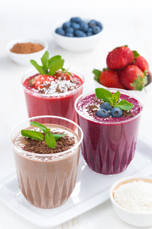 Assorted milkshakes - strawberry, blueberry and chocolate and ingredients, vertical, close-upの写真素材