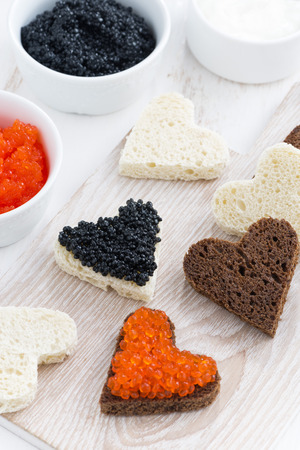 festive appetizer - toasts in heart shape on wooden board , vertical, top viewの写真素材