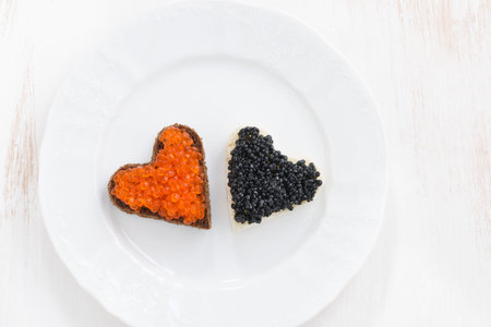 festive appetizer - toasts in heart shape on white plate, top view, horizontalの写真素材