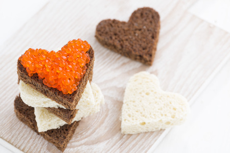 toasts with red caviar in heart shape on wooden board, top viewの写真素材
