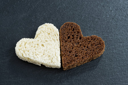 toasted rye and white bread in the form of heart on a black background, close-up, top view, horizontalの写真素材