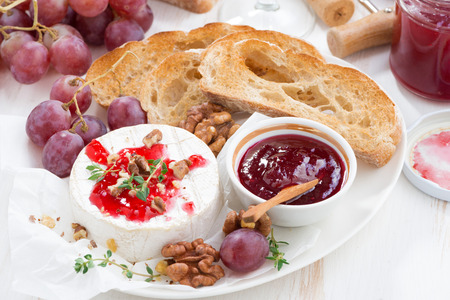 appetizers for wine - camembert with berry jam, toast and fruit on white table, top view, horizontalの写真素材