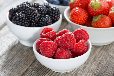 raspberries in a bowl and fresh garden berries, close-up