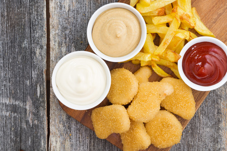 chicken nuggets with french fries and different sauces on board, top view, horizontalの写真素材