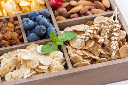 assortment of breakfast cereal, dried fruit, berries and nuts in a wooden box, closeup, horizontalの写真素材