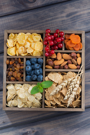 breakfast cereal, dried fruit, berries and nuts in a wooden box, verticalの写真素材