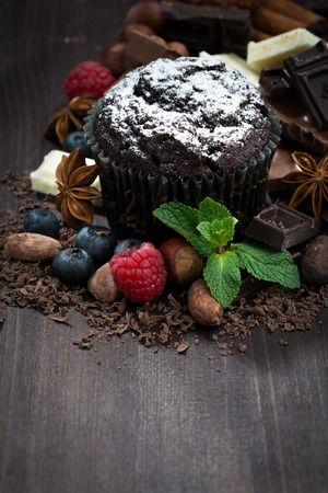 chocolate muffins with icing sugar and ingredients on dark wooden background, vertical, top viewの写真素材
