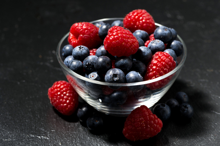 fresh berries in a glass bowl on black background, horizontalの写真素材