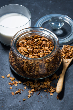 homemade baked granola in a glass jar on dark background, top viewの写真素材