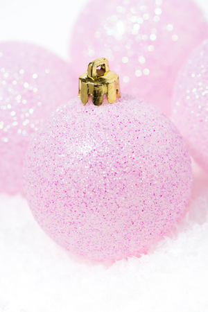 festive pink Christmas balls in the snow on a white background, vertical closeupの写真素材