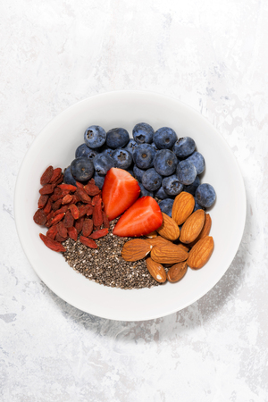 chia seeds, berries and nuts for a healthy breakfast, vertical top viewの写真素材
