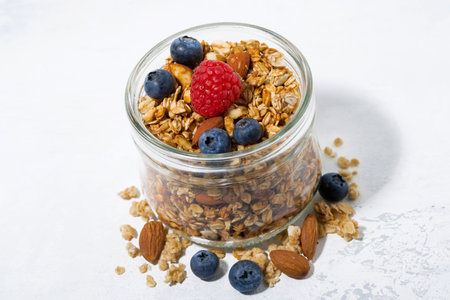 homemade muesli in a glass jar on a white background for healthy breakfast, top view horizontal