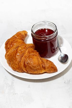 fresh croissant on a plate and strawberry jam, vertical top viewの写真素材